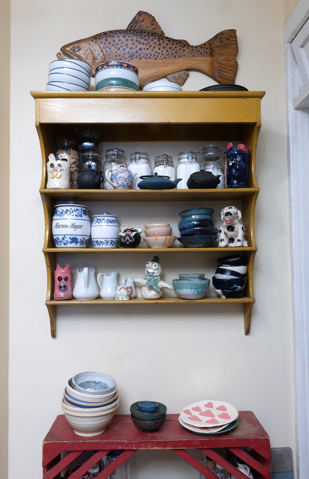 Handmade bowls and ceramic characters on the shelves in Sam’s kitchen