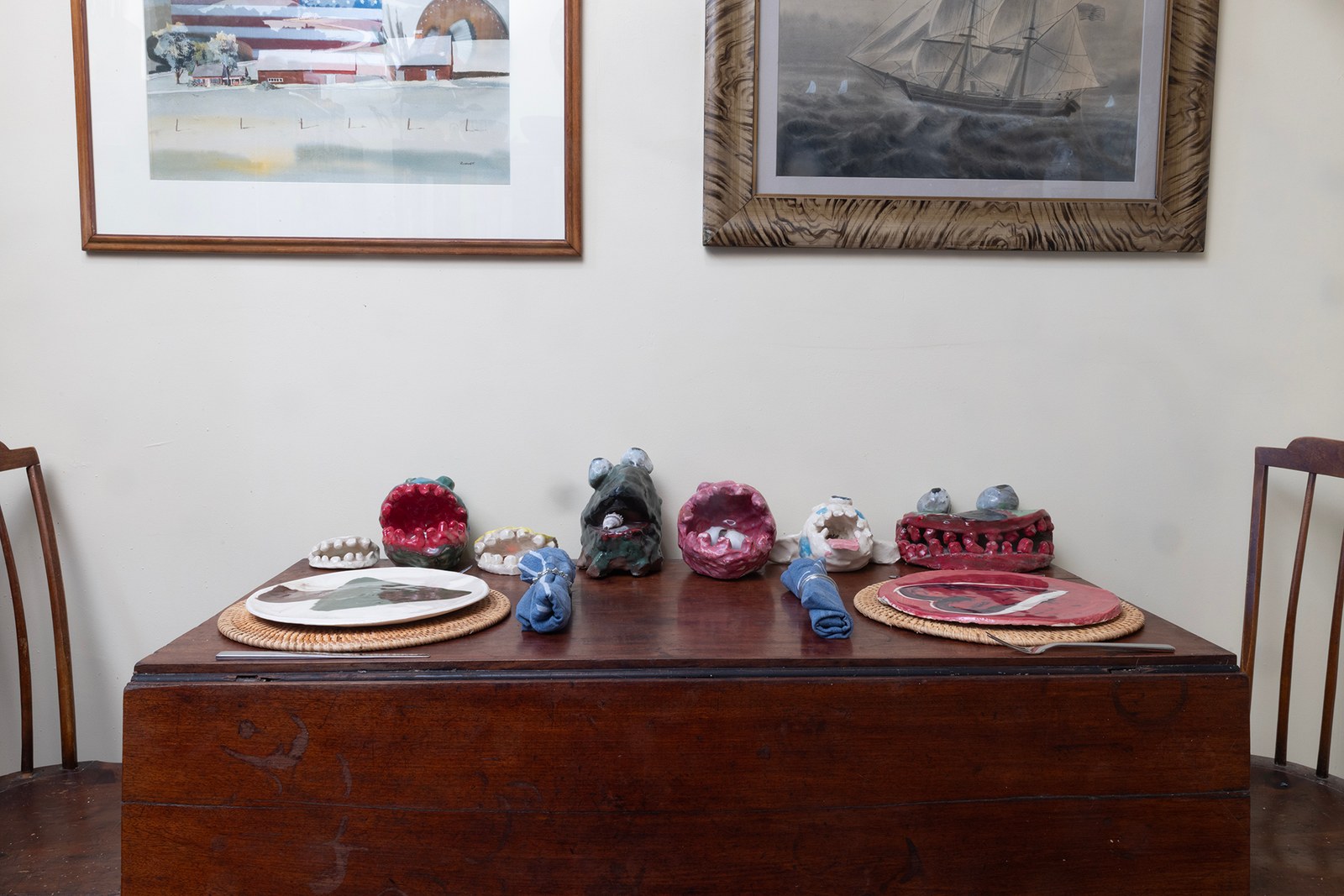 Sam’s handmade ceramics arranged on a dining table beneath framed art