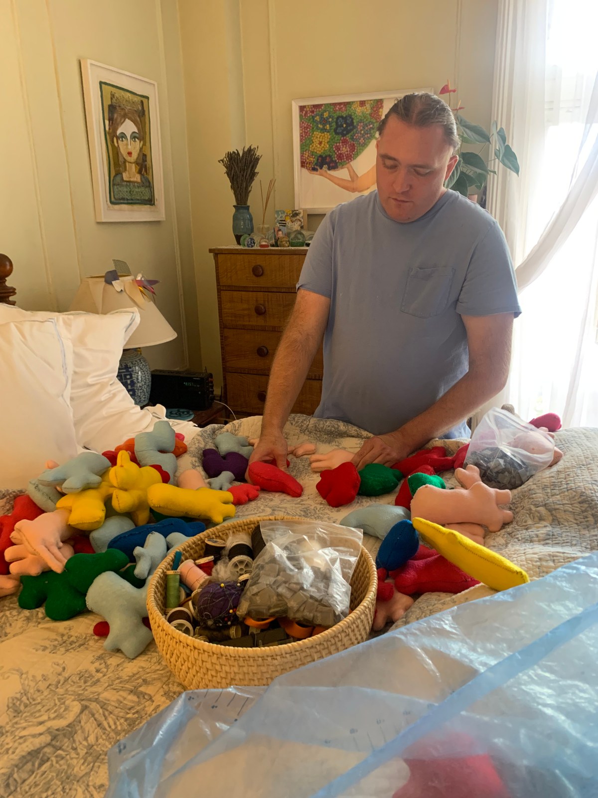 Sam sewing and preparing a colorful collection of handmade doll bodies