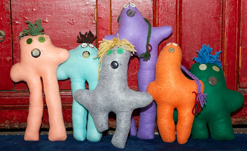 Six handmade felt dolls with button faces and colorful yarn hair